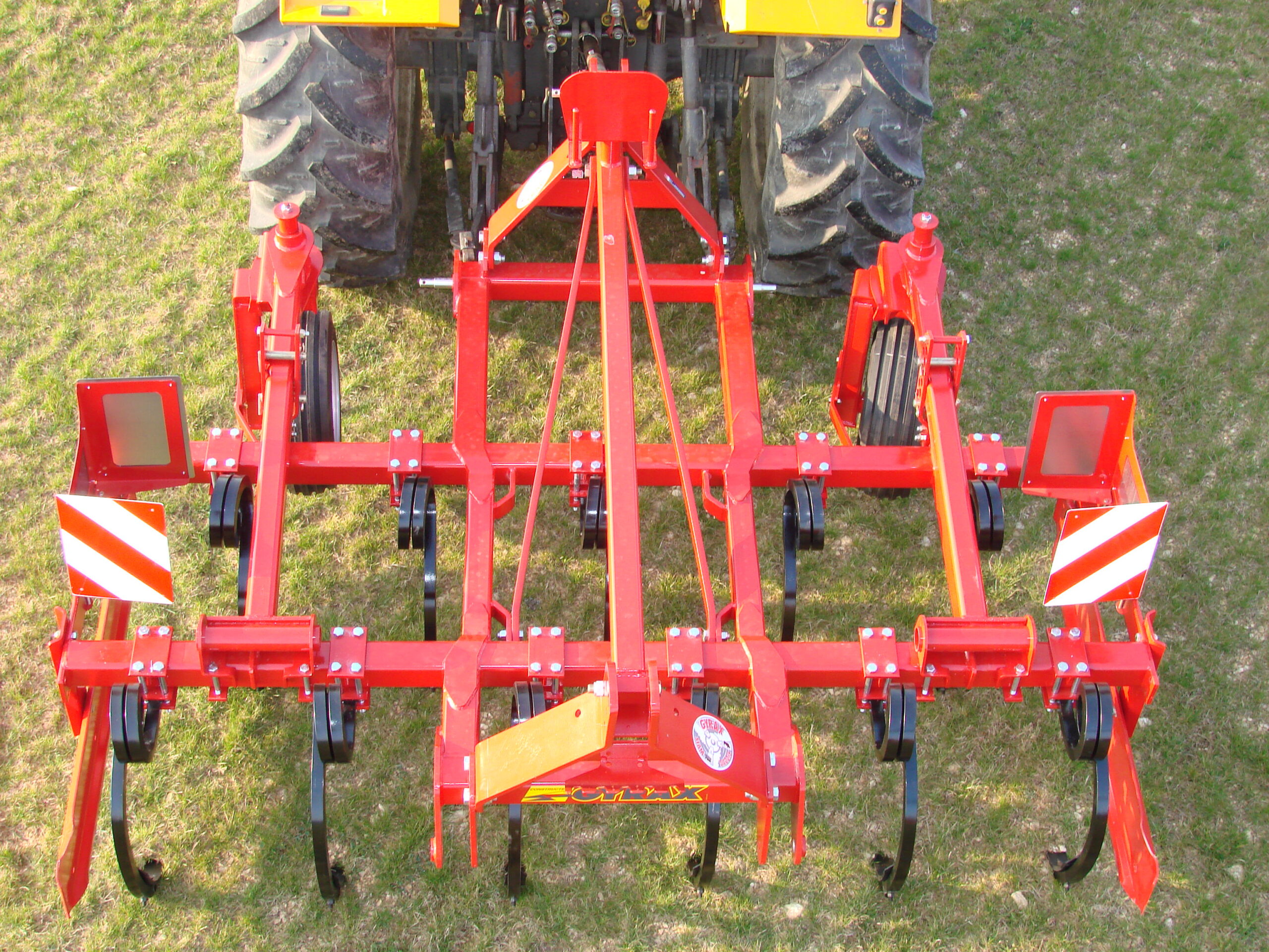 Cultivateur fixe rouge de marque Gyrax, modele, 2 poutres, à l'arrière d'un tracteur. Vue arrière plongeante