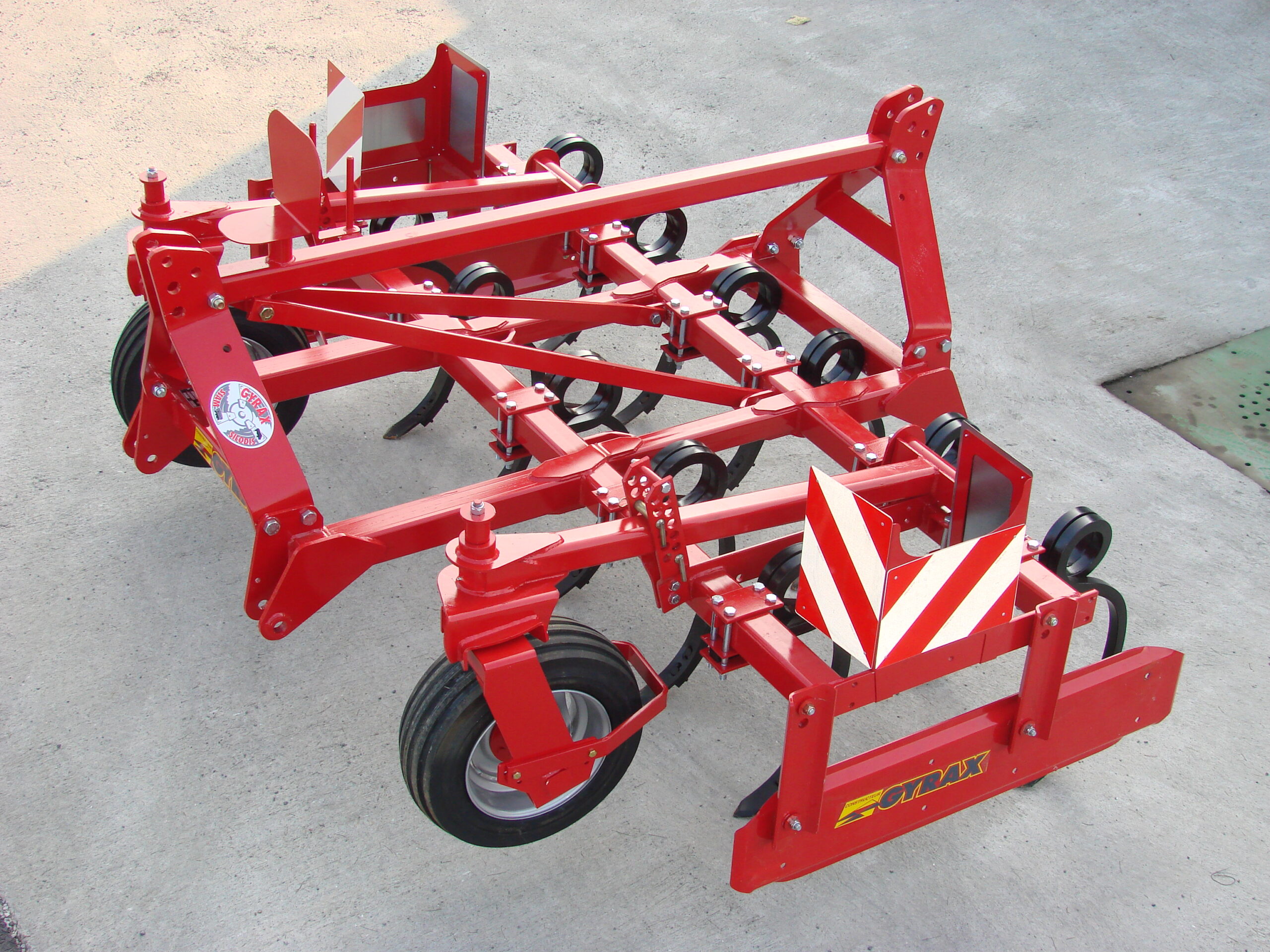 Cultivateur fixe rouge de marque Gyrax, modele, 2 poutres. Au sol sortie d'usine