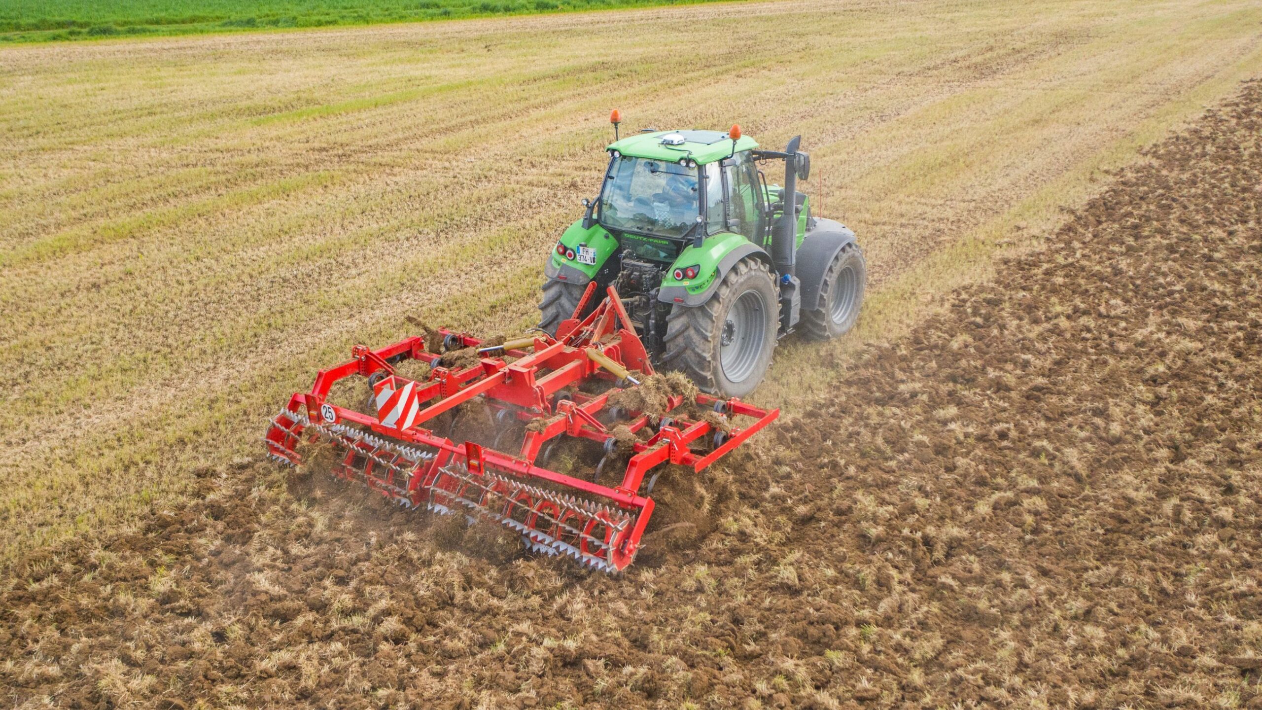Cultivateur 3 poutres repliable rouge de marque Gyrax, dans un champs vu du ciel, ou l'on voit le résultat efficace de son passage avant apres.