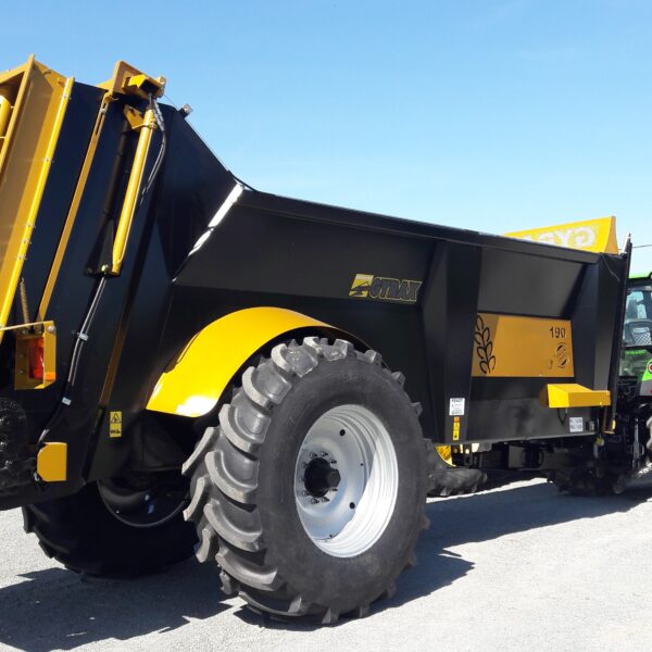 élégant épandeur noir et jaune de marque Gyrax, modèle 190, tracté et sortant d'un parking.