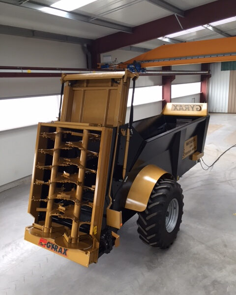 Epandeur à fumier EDHV 190 Gyrax, de couleur noir et or, stocké en intérieur de l'usine, sur un sol béton épuré et élégant.