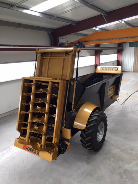Epandeur à fumier EDHV 190 Gyrax, de couleur noir et or, stocké en intérieur de l'usine, sur un sol béton épuré et élégant.