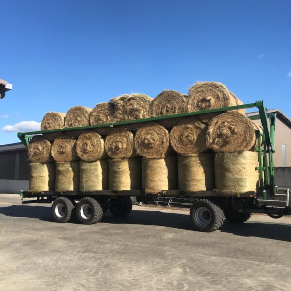 Plateau fourrager tourelles vert de marque Gyrax, chargé de botte de paille rondes