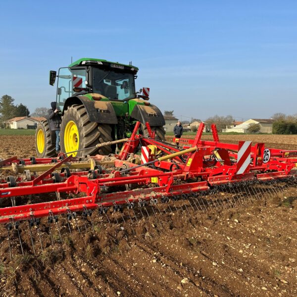 Vibroculteur Gyrax rouge, au milieu d'un champs, vu au sol arrière