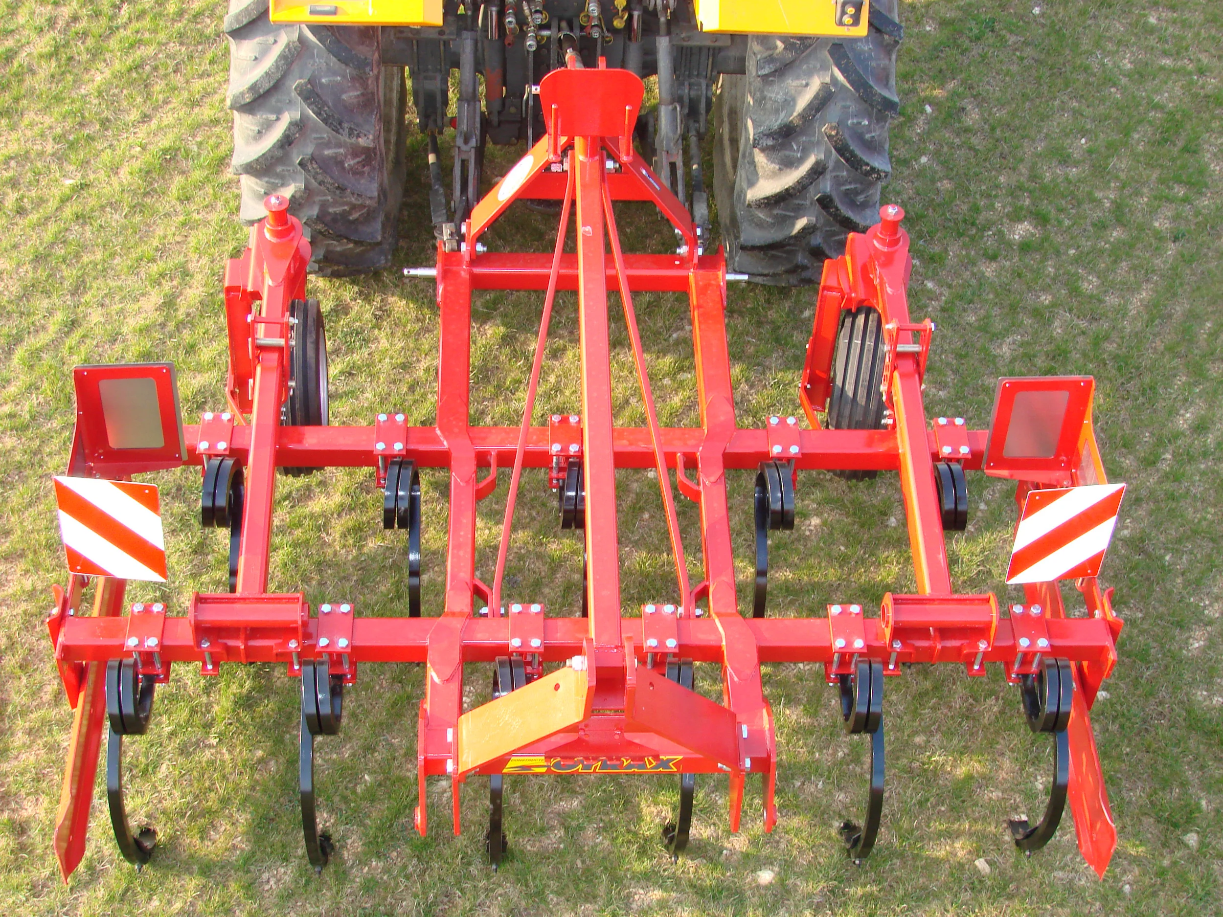 Cultivateur fixe rouge de marque Gyrax, modele, 2 poutres, à l'arrière d'un tracteur. Vue arrière plongeante