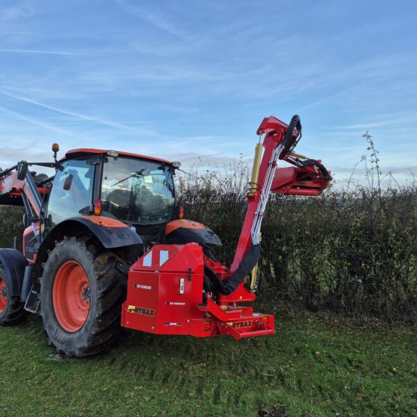 epareuse Gyrax au travail, avec le bas avancé au dessus d'une haie
