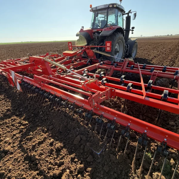 vue arrière 3/4 d'un vibroculteur dans un champs, attelé.