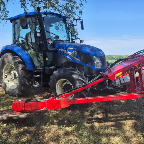 Broyeur sous cloture Gyrax attelé à l'avant d'un tracteur, en action contre un pied d'arbre.